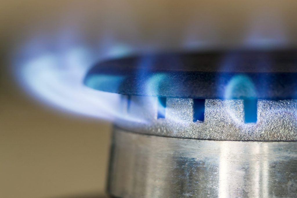 The even blue flames of a lit gas burner, close up
