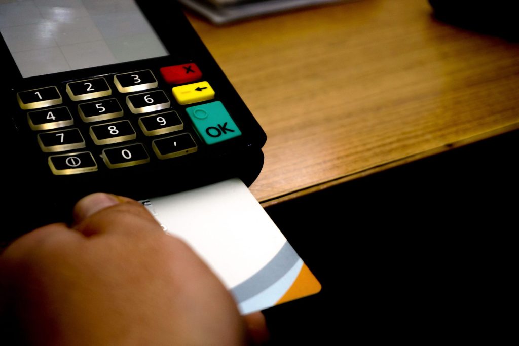 A card terminal printing a receipt on a wooden counter
