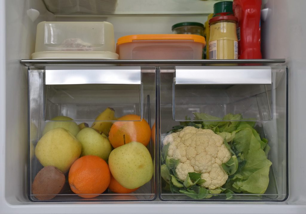 Pears, oranges and cauliflower in the clear crisper drawers of a refrigerator