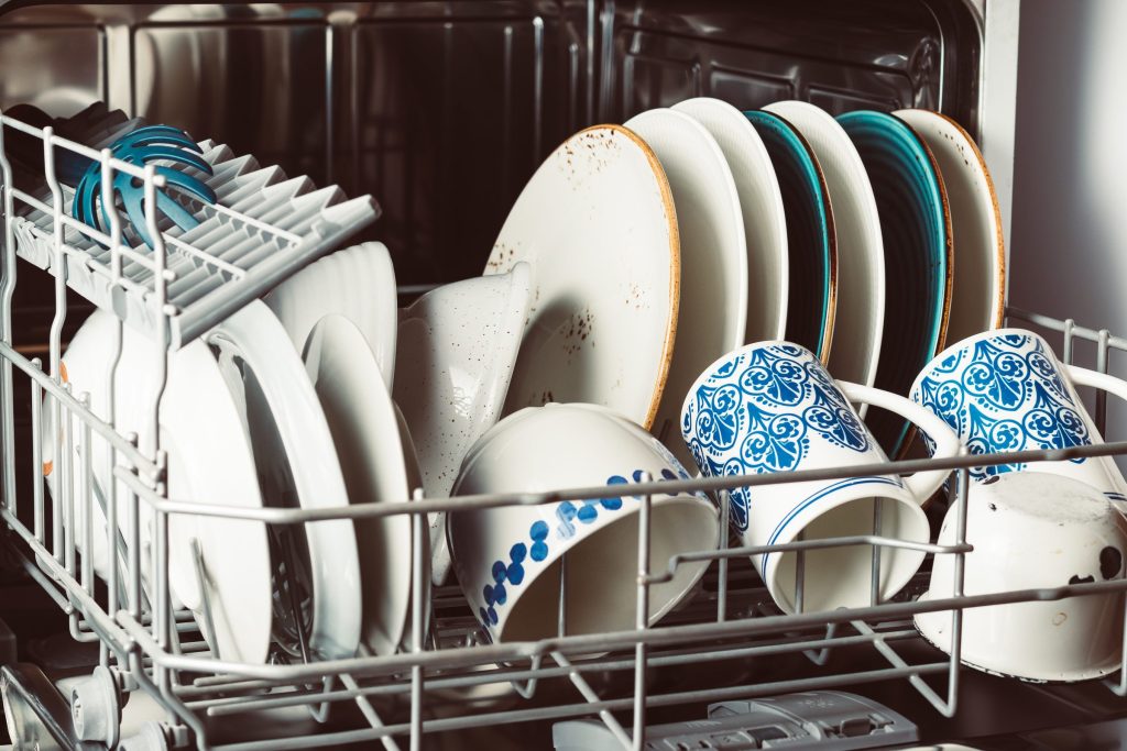 Patterned mugs and plates in the racks of a dishwasher