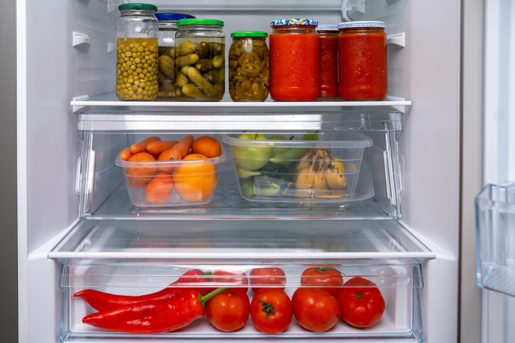 Preserving jars and drawers of vegetables on the shelves of a refrigerator