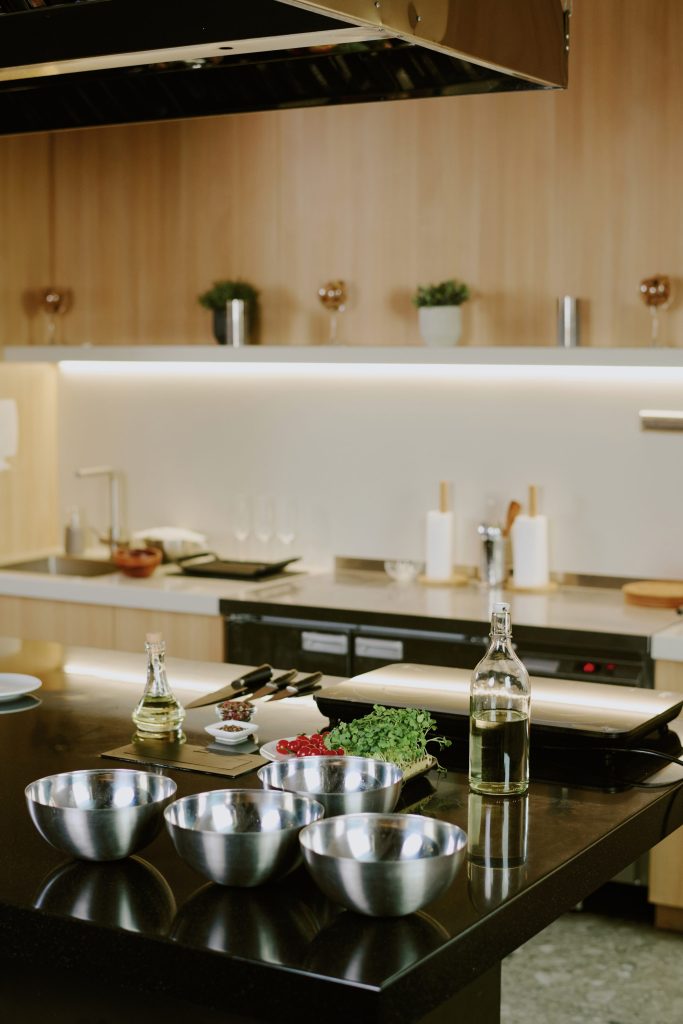 A dark island laid out for cooking under a lit hood