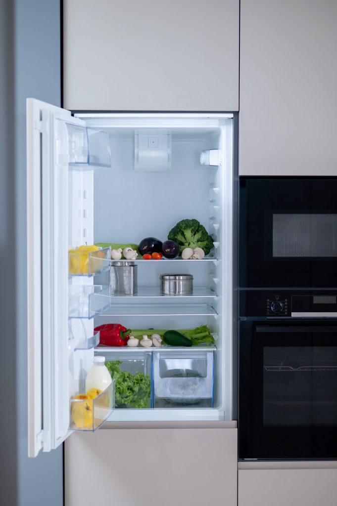 An integrated refrigerator standing open in a dark cabinet run