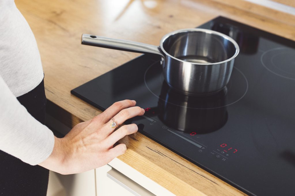 A pan on a black induction surface set flush into a wooden counter