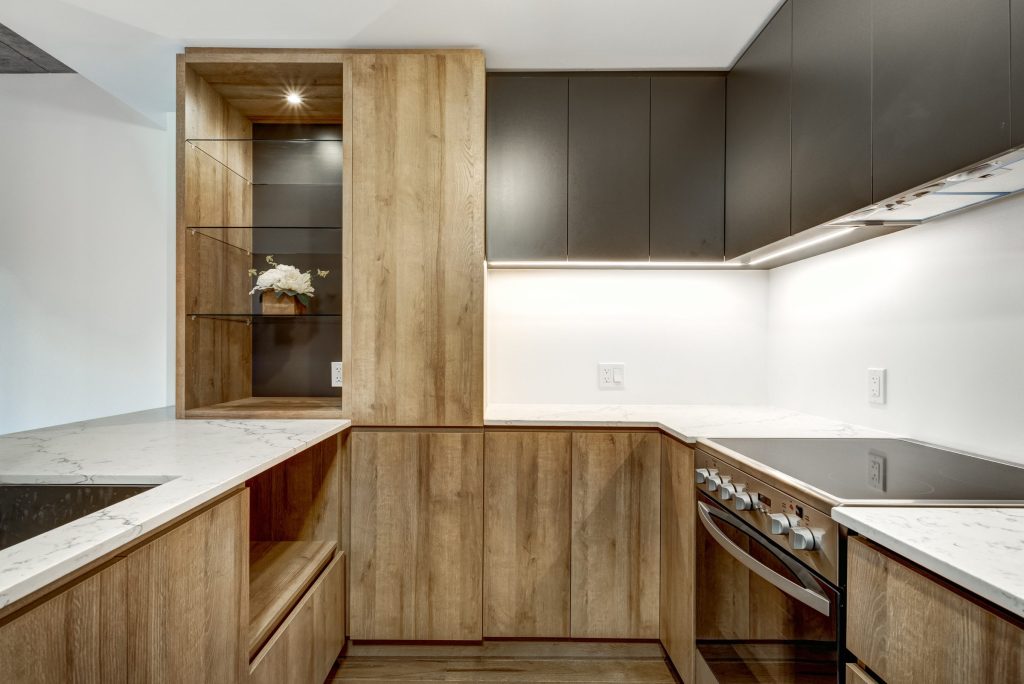 An oak galley kitchen with a flush cooktop and a built-in oven under the counter