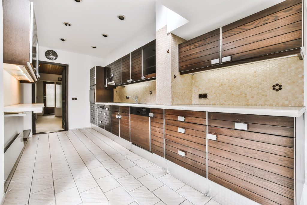 A wood-fronted galley kitchen with a tiled splashback and a run of upper cabinets