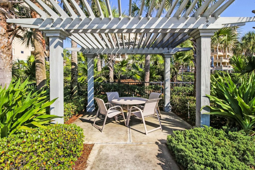 A pergola and a table in a planted courtyard