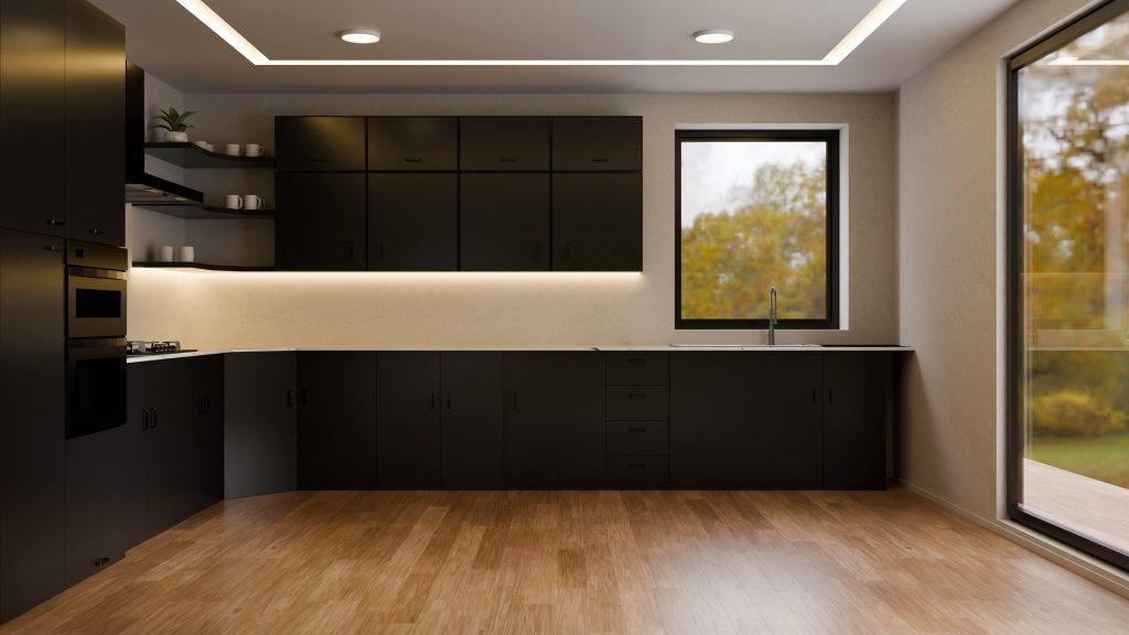 A black kitchen run along one wall with a lit worktop, wooden floor and a window onto the garden