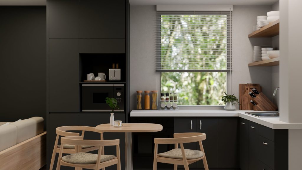 A dark green kitchen with a round wooden table and a window over the sink
