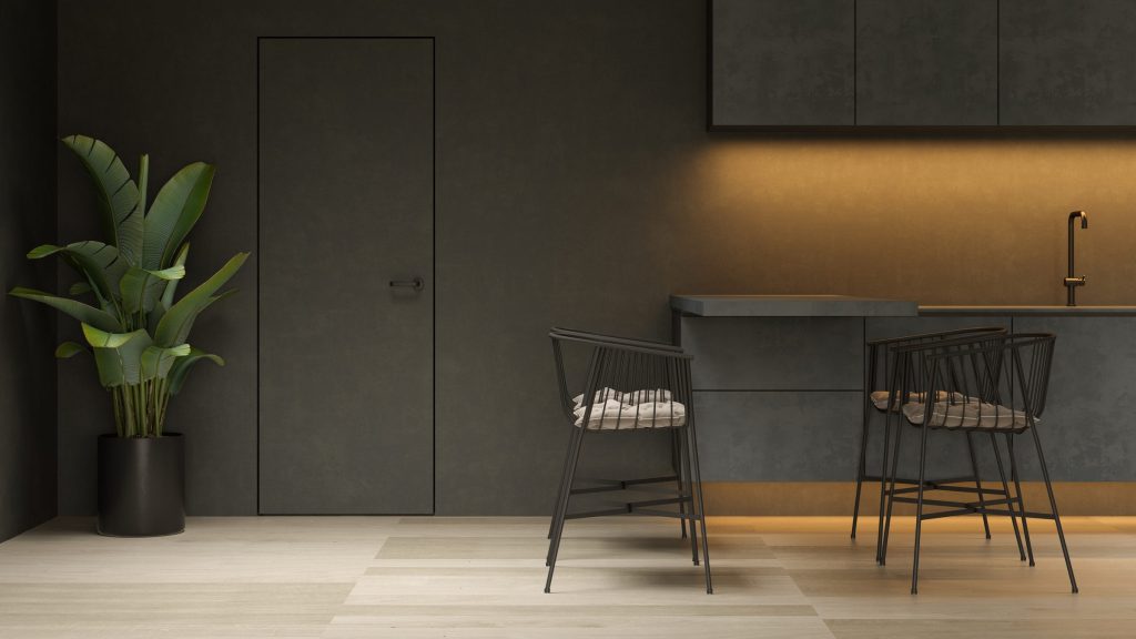 An olive-toned kitchen corner with two bar chairs and a tall plant beside the door
