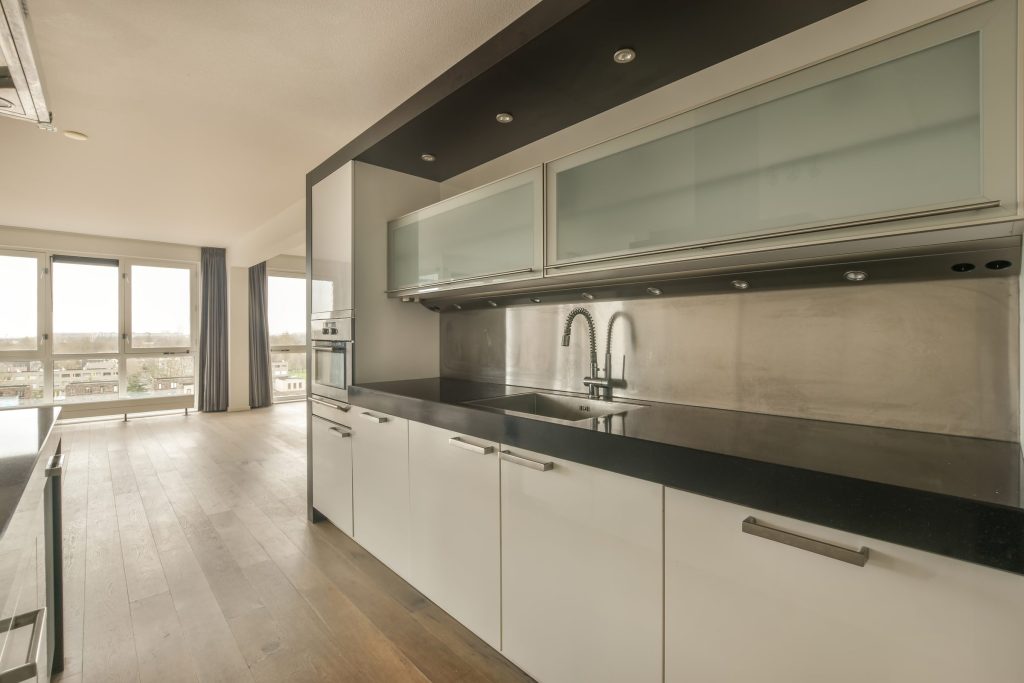 A long steel and white galley kitchen with windows onto the dunes