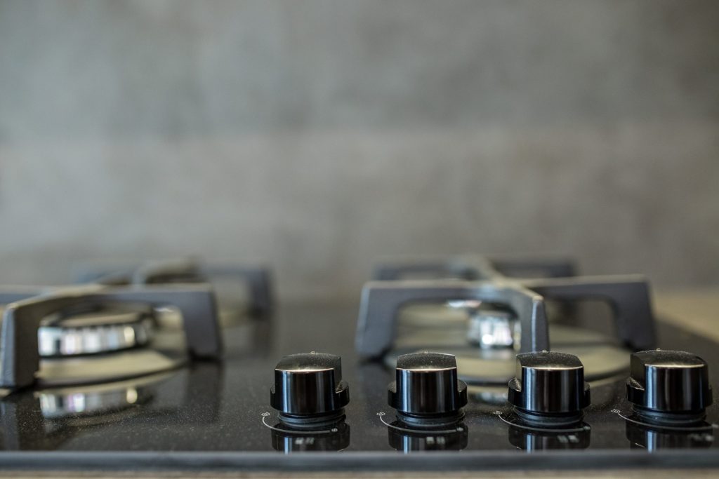 Sealed gas burners and their control knobs, close up on a dark cooktop