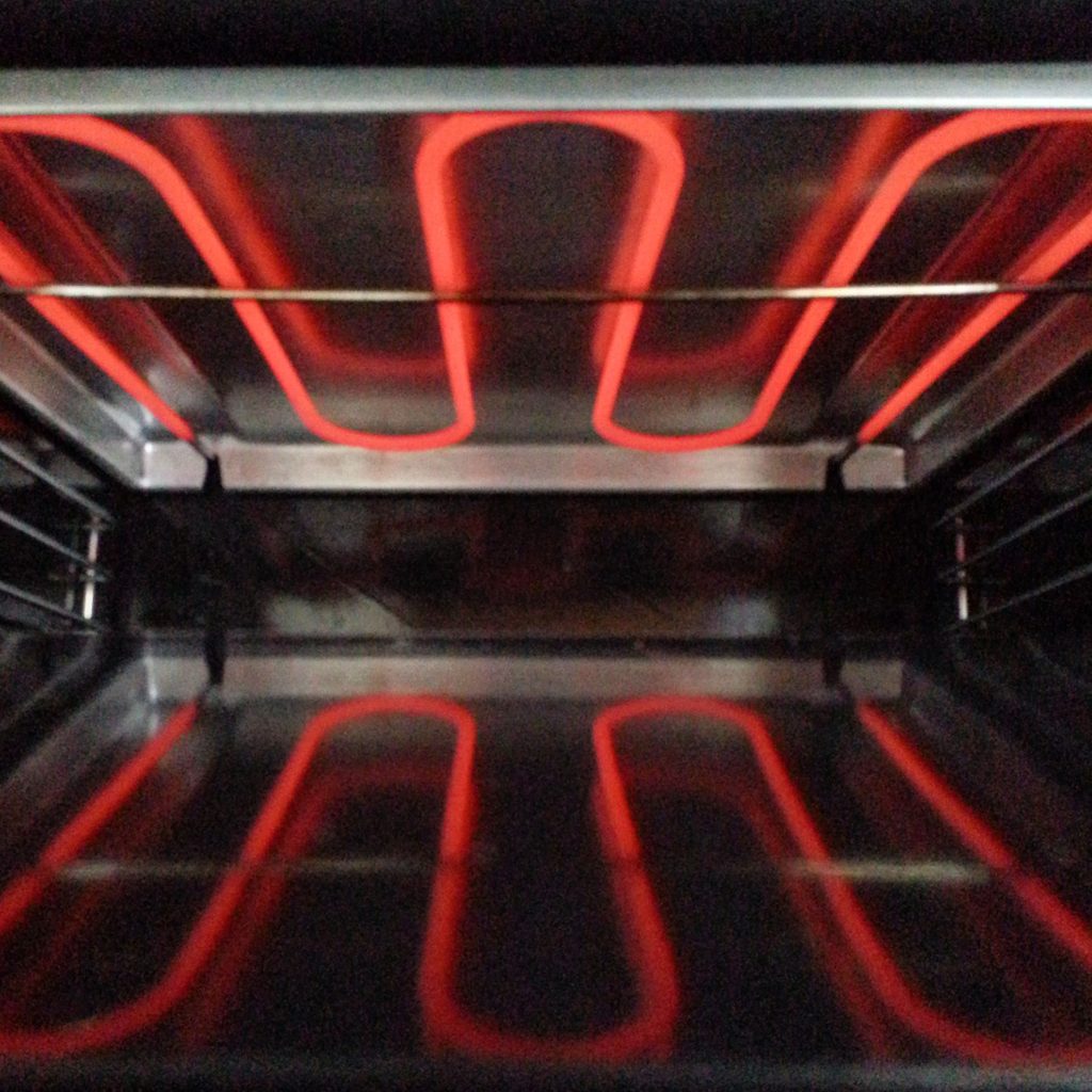 The grill element glowing red across the roof of an oven cavity