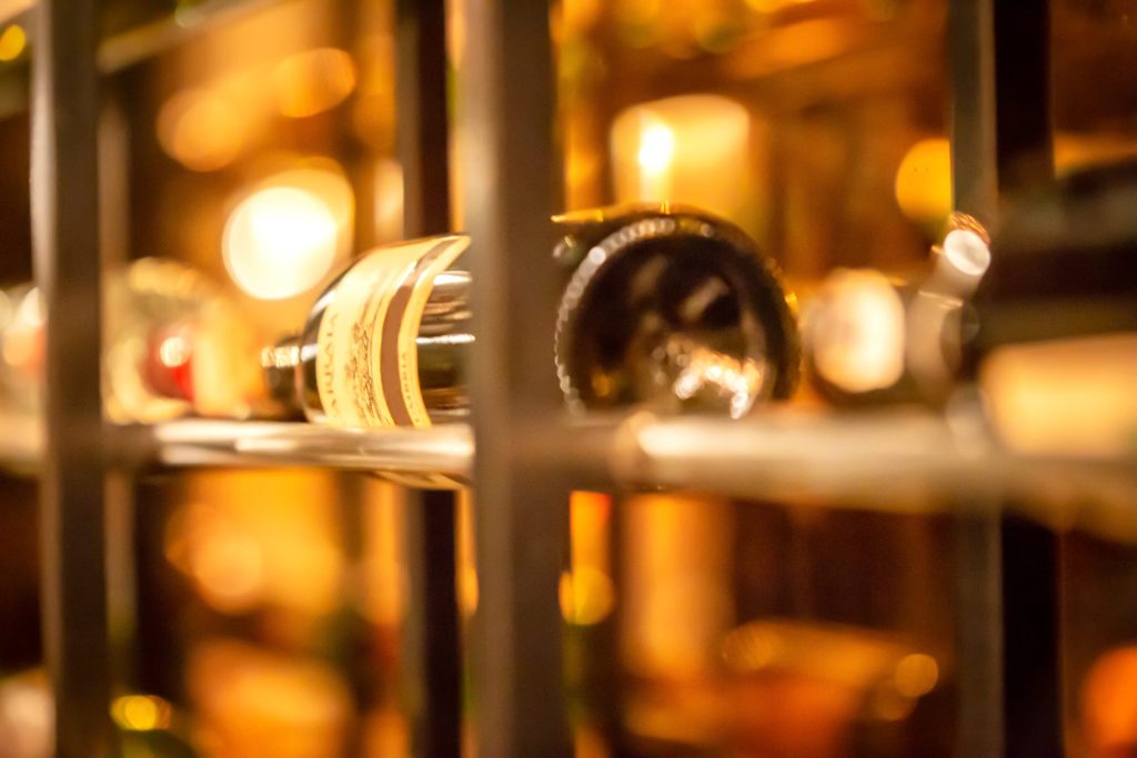 A wine bottle resting on a metal rack in a warmly lit cabinet