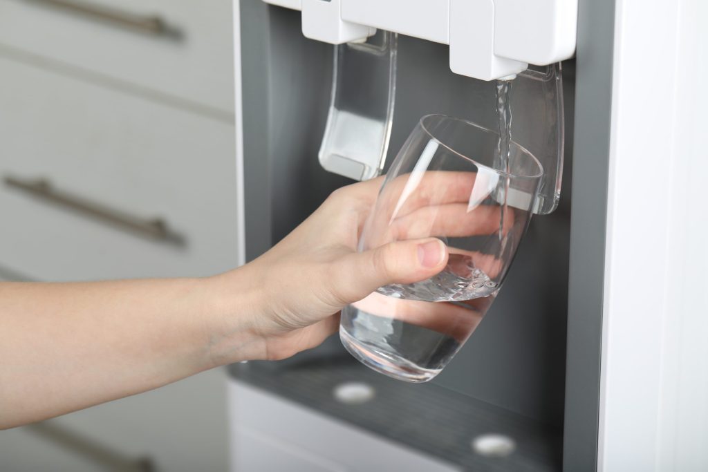 A hand holding a glass under the water dispenser recess of a built-in refrigerator