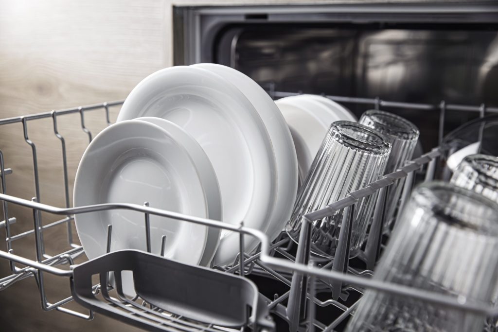 Glasses and plates standing in a dishwasher rack after a cycle