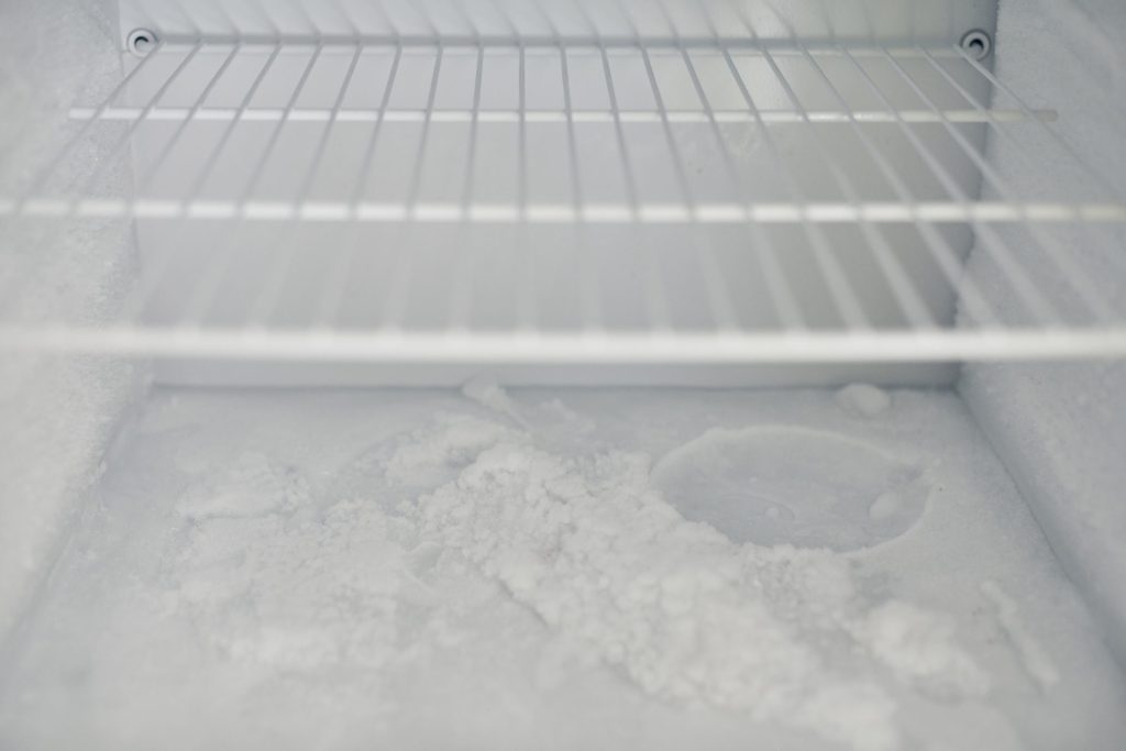 Frost lying across the wire shelf and floor of a freezer compartment