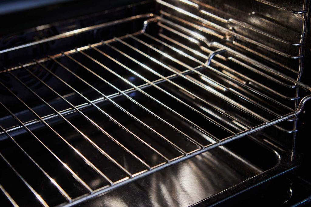 A clean empty oven with a wire rack, lit from inside