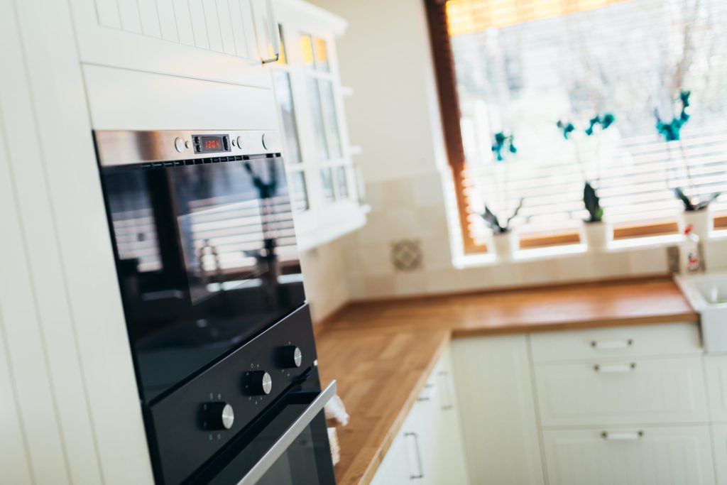 A black oven set under the counter in a bright kitchen