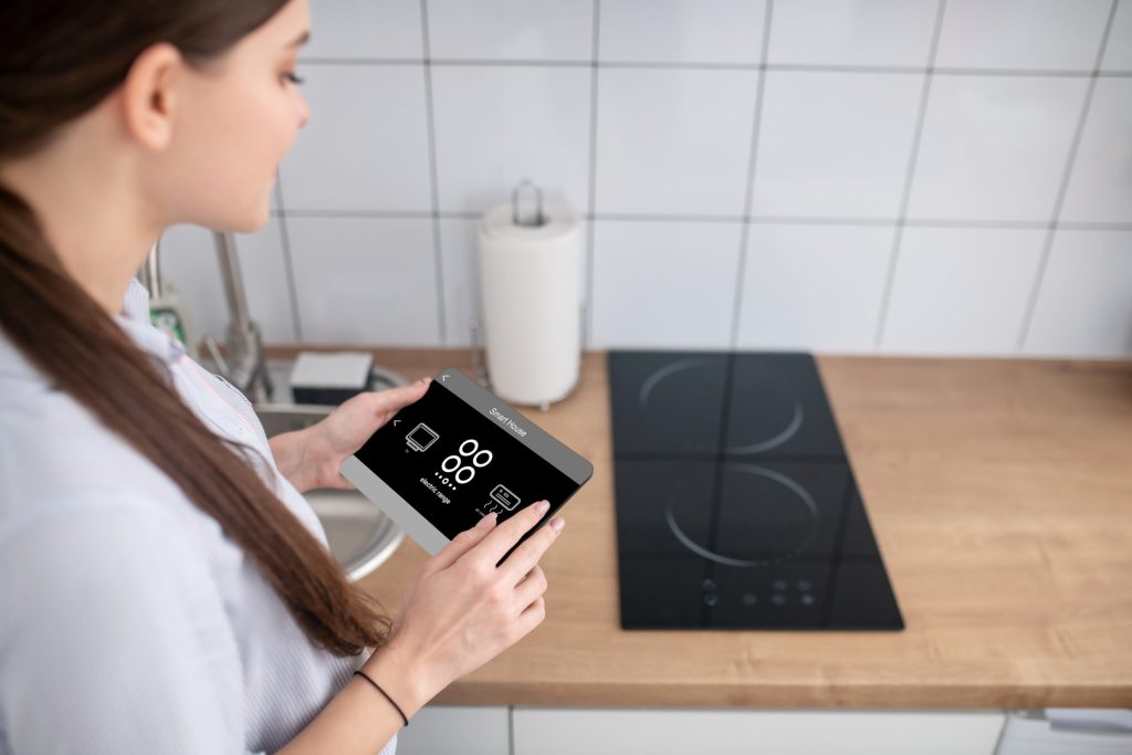 A tablet held beside an induction cooktop set into a wooden counter