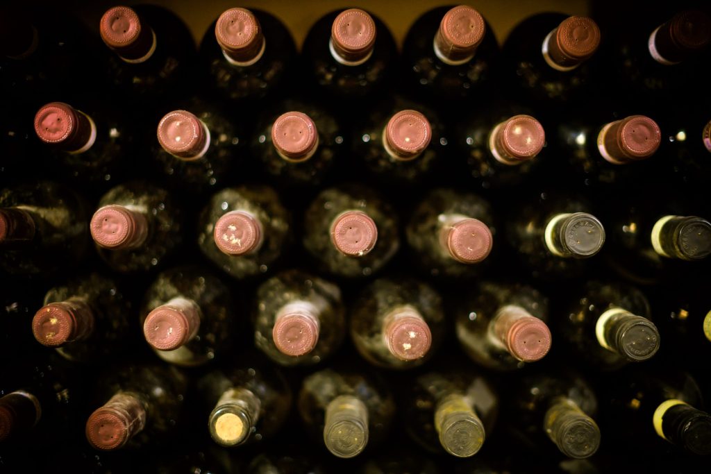 Rows of wine bottles stored on their sides in a dark cabinet