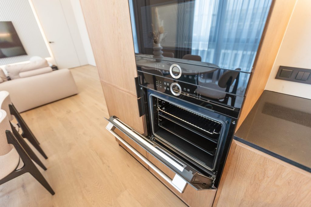A black double wall oven built into a wood column, the lower door standing open
